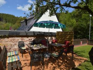 a patio with chairs and a table and an umbrella at Holiday home with garden in Hellenthal Eifel in Hellenthal