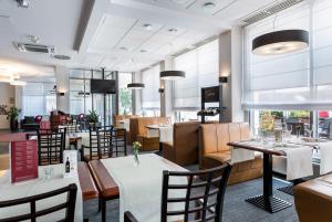 a restaurant with tables and chairs and windows at Qubus Hotel Gliwice in Gliwice