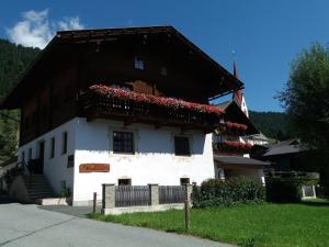 a white house with red flowers on the balcony at Haus Antonius in Sankt Lorenzen im Lesachtal