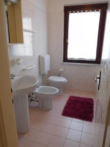 a bathroom with a sink and a toilet and a window at Casa Pastoricchio in Grado