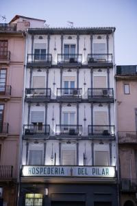 Un alto edificio bianco con un cartello sopra di Hospederia del Pilar a Valencia