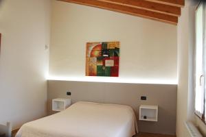 プロヴァーリオ・ディゼーオにあるVilla Pasiniの白いベッドと壁に絵画が飾られたベッドルーム1室
