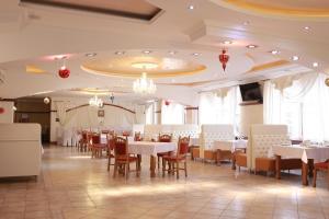 a dining room with white tables and chairs at Hotel Smaragd in Nadvirna