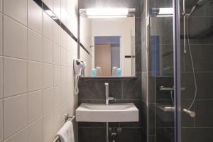 a bathroom with a sink and a mirror at Bastion Hotel Leeuwarden in Leeuwarden