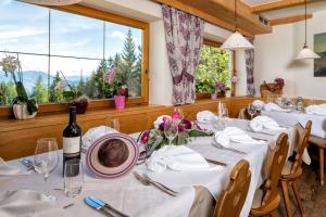 a dining room with white tables and a large window at Hotel Wiesl in Collepietra