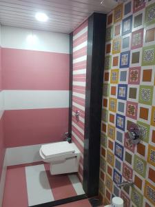a bathroom with a toilet and a colorful wall at Hotel Laabh in Diu +14 photos