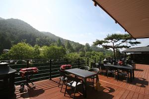een terras met tafels en stoelen en uitzicht op een berg bij CAMP Jirisan Parkview in Gurye