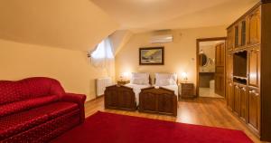 uma sala de estar com uma cama e um sofá vermelho em Vinum Hotel em Kiskorös
