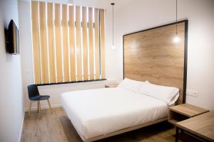 a bedroom with a white bed and a chair at Somn Hipsuites Zarautz in Zarautz