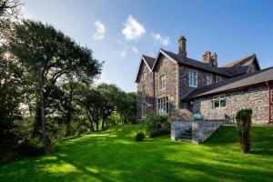 an old stone house with a green yard at Penrhiw Priory in St. Davids