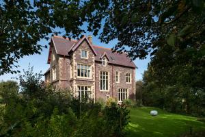 a large brick house on a green lawn at Penrhiw Priory in St. Davids
