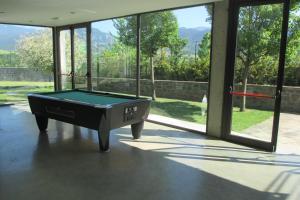 a pool table in the middle of a room with windows at Alberg la Bruna in Bellver de Cerdanya 