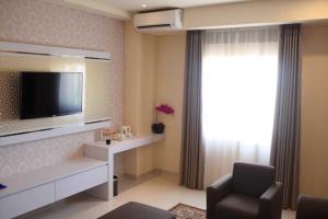 a living room with a flat screen tv and a chair at Namira Syariah Hotel Surabaya in Surabaya