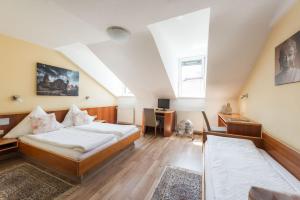 a attic bedroom with two beds and a desk at City Hotel Konstanz in Konstanz