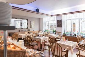 ein Restaurant mit Tischen, Stühlen und Fenstern in der Unterkunft City Hotel Konstanz in Konstanz