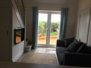 a living room with a couch and a sliding glass door at Little Fernleigh in Perranporth