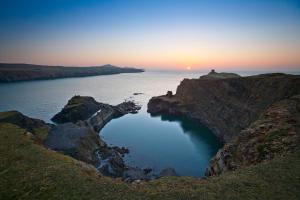 a large body of water with the sunset in the background at Penrhiw Priory in St. Davids