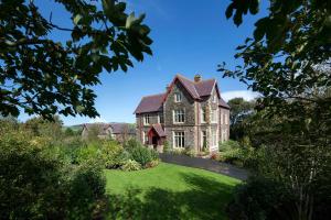 an old house with a green lawn in front of it at Penrhiw Priory in St. Davids