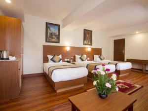 a hotel room with two beds and a table with flowers at Oasis Kathmandu Hotel in Kathmandu