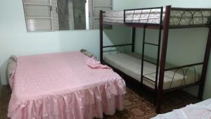 a bedroom with two bunk beds with a pink sheet at Pousada Tutubarao in Itirapina