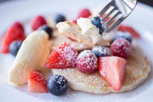 a plate with fruit on top of pancakes with a fork at Penrhiw Priory in St. Davids