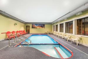 una piscina en una habitación con sillas y TV en Days Inn & Suites by Wyndham Youngstown / Girard Ohio, en Girard