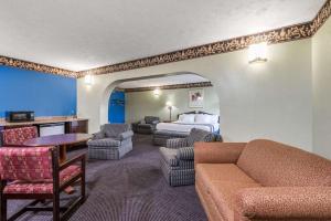 a hotel room with a bed and a couch and chairs at Days Inn & Suites by Wyndham Youngstown / Girard Ohio in Girard