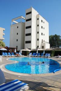 a pool with chairs and people in the water at Pigeon Beach Hotel Apartments in Limassol