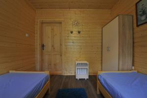 two beds in a room with wooden walls at Domki nad Soliną 665-189-444 in Solina