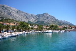 a group of boats docked in a river with mountains at Apartment Andrija in Baška Voda