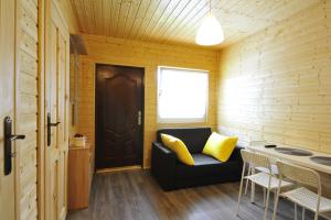 a living room with a black couch and yellow pillows at Domki nad Soliną 665-189-444 in Solina