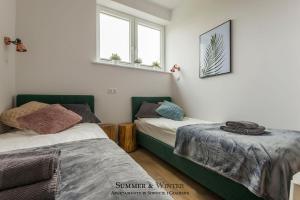 a bedroom with two beds and two windows at Family Luxury Green Apartment 1-6, 2 sypialnie i studio, 52 m2 in Gdańsk