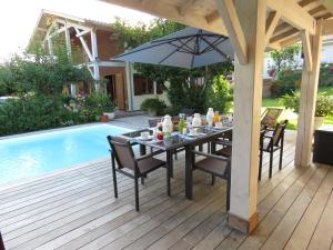 a table with an umbrella on a deck next to a pool at Les Arums de Fondeminjean in Vertheuil-en-Médoc