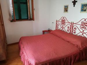 una camera con letto rosso e piumone di Casa nei boschi della Val Bormida a Calizzano