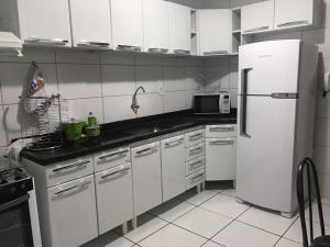 a kitchen with white cabinets and a white refrigerator at Recanto Lili in Olímpia