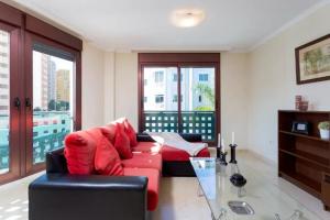 sala de estar con sofá rojo y mesa de cristal en Apartamento La Salle, en Santa Cruz de Tenerife