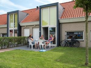 Un groupe de personnes assises à une table à l'extérieur d'une maison dans l'établissement Vakantiepark Broedershoek, à Koudekerke