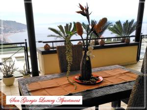 un vase assis sur une table sur un balcon dans l'établissement San Giorgio Luxury Apartment Taormina-Panoramic Pool & Parking Space, à Taormine