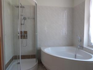 La salle de bains est pourvue d'une baignoire et d'une douche en verre. dans l'établissement La petite maison de Lilou, à Romilly-sur-Seine