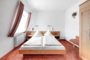 a bedroom with a bed with white sheets and pillows at Gasthof - Hotel Kopf in Riegel am Kaiserstuhl