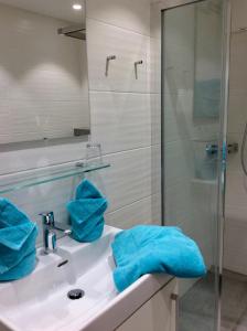 La salle de bains est pourvue d'un lavabo et d'une douche avec des serviettes bleues. dans l'établissement Studio Hanna, à Kaprun