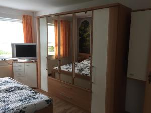 ノイシュトレーリッツにあるFerienwohnung Neustrelitzのベッドルーム1室(テレビ付きの大きな木製キャビネット付)