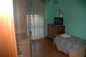 ein Schlafzimmer mit einem Bett und einem TV auf einer Kommode in der Unterkunft Hotel Valentino in Perosa Argentina