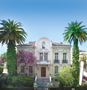 une maison avec deux palmiers devant elle dans l'établissement Résidence La Villa Léonie, à Nice