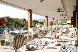 a restaurant with white tables and chairs on a patio at Alexandra Golden Boutique Hotel-Adults Only in Chrysi Ammoudia