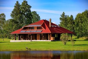 uma casa com um telhado vermelho ao lado de um lago em Agave em Augšlīgatne