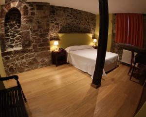 a bedroom with a bed and a stone wall at Hotel Casona Cuervo in San Tirso de Candamo