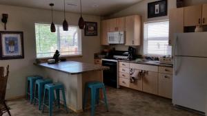 eine Küche mit einem weißen Kühlschrank und blauen Stühlen in der Unterkunft Grizzly Roadhouse Bed and Breakfast in Cortez