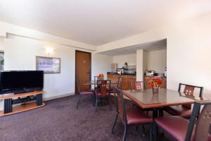 Executive Plus Inn and Suites في إيلك سيتي: غرفة طعام مع طاولة وتلفزيون
