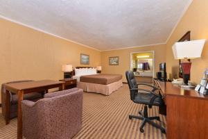 Executive Plus Inn and Suites في إيلك سيتي: غرفة في الفندق مع غرفة نوم مع سرير ومكتب